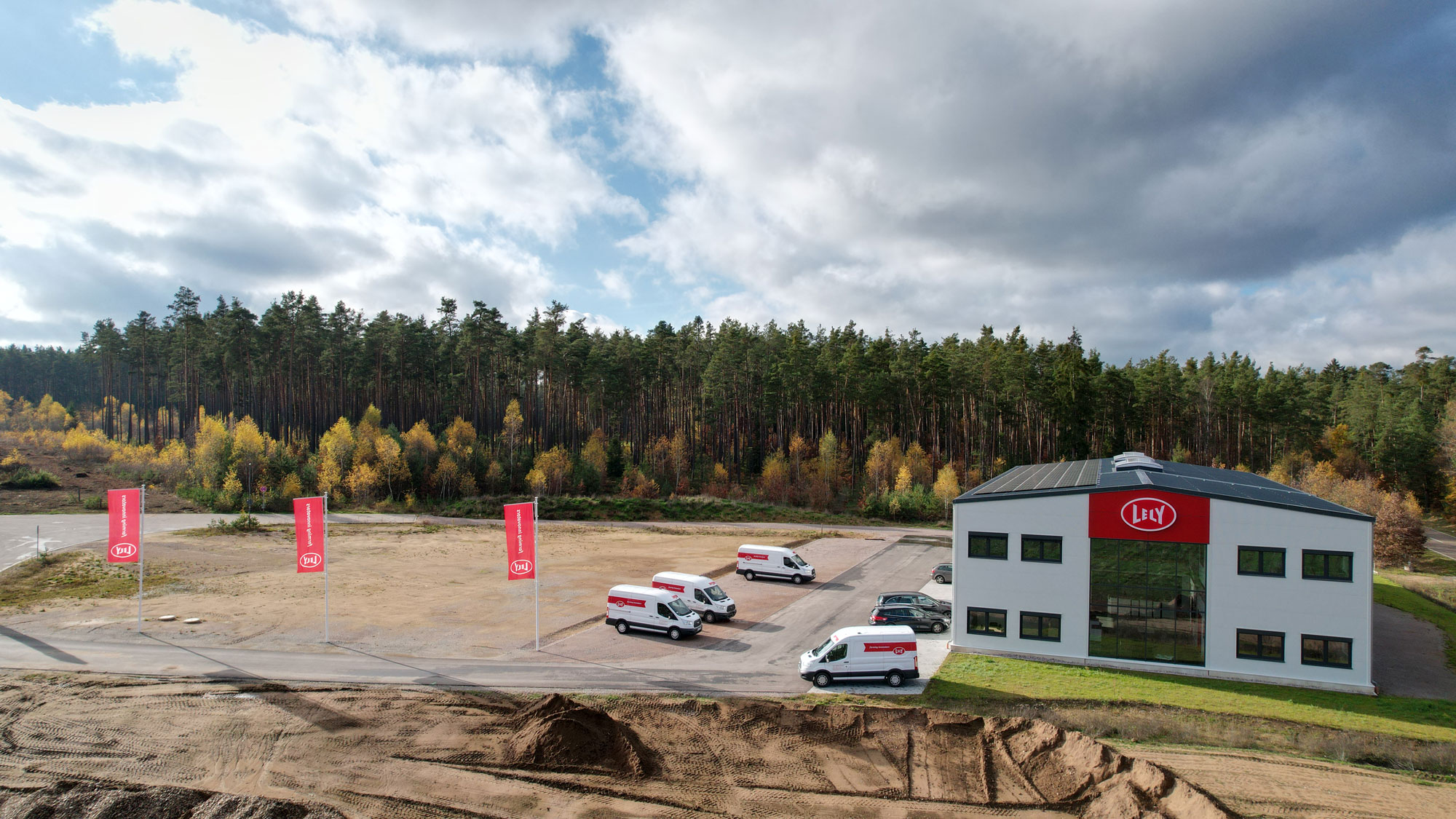 ely Betriebsgebäude mit Servicefahrzeugen und roten Lely-Fahnen